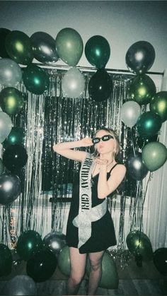 a woman standing in front of balloons and streamers with her hand on her hip