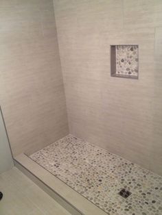 a white tiled shower stall with an open window in the wall and tile flooring