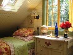 two beds in a room with yellow curtains on the window sill and green bedding