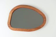 a wooden mirror on a white wall with a reflection in the mirror that is shaped like an oval