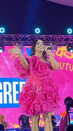 a woman in a pink dress singing on stage