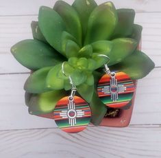 Zia Round Serape Earrings, New Mexico Serape Earrings, Southwestern Earrings, Western Earrings, Zia Jewelry, New Mexico Jewelry.  These lightweight earrings are perfect statement of the Southwest.  Earring is a lightweight wood printed with a vibrant serape print.  Final touch to adorn these precious earrings is a stainless-steel Zia charm.  These will for sure be your favorite earrings.  Perfect with any outfit and so light you won't even remember you are wearing them.  Get your today, they come in this multicolor serape print or check our page for other prints. Southwestern Style Dangle Hoop Earrings As Gift, Bohemian Concho Earrings As Gift, Artisan Concho Earrings As Gift, Southwestern Style Drop Earrings As Gift, Southwestern Dangle Hoop Earrings As Gift, Southwestern Style Festival Round Earrings, Southwestern Style Round Festival Earrings, Adjustable Concho Earrings For Festival, Concho Dangle Earrings For Gift