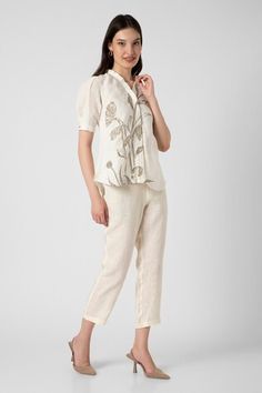 Off-white top with dainty bloom print and zari stitch line on hem. Paired with pant. - Aza Fashions Off White Floral Print Sets For Spring, Spring Cotton Trouser Sets, Spring Cotton Sets With Trousers, Cream Sets For Workwear In Spring, Spring Off White Floral Print Sets, Elegant White Pants With Floral Embroidery, Floral Embroidered Pants For Spring Workwear, White Relaxed Fit Sets For Spring, Spring Sets With Relaxed Fit Trousers