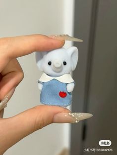 a hand holding a small blue and white stuffed animal