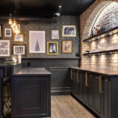 a bar with pictures on the wall and stools in front of it, next to an island