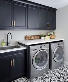 a washer and dryer in a room with black cabinets, white counter tops