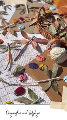 an assortment of crochet hooks and needles on a table with paper leaves, scissors and other crafting supplies