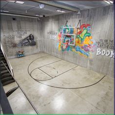 an indoor basketball court with graffiti painted on the walls and in the middle of it