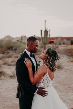 a bride and groom standing together in the desert