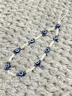 an eye beaded necklace is laying on a white knitted surface with blue beads