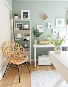 a living room with a wicker chair in the corner and various pictures on the wall