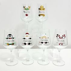 four wine glasses with different designs on them and one has an image of a penguin