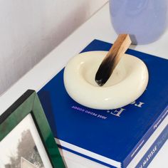 a white object sitting on top of a blue book next to a framed photo and a wooden stick