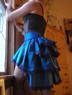 a woman in a blue and black dress looking out the window