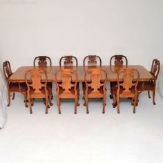 a dining room table and six chairs with white walls in the backround area