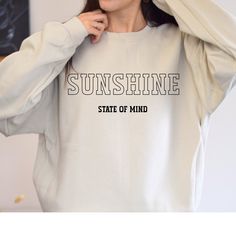 Introducing the Gildan Crew Neck Sweatshirt, a cozy essential that captures the carefree vibe of a sunny state of mind. Crafted for comfort and style, this sweatshirt is your go-to choice for relaxed days and laid-back adventures. Emblazoned across the chest in classic University Style Font is the phrase "Sunshine State of Mind," evoking feelings of warmth, positivity, and endless possibilities. Whether you're soaking up the sun on the beach or strolling through city streets, this sweatshirt embodies the easygoing attitude of a sunny day. Made from soft, high-quality fabric and featuring a timeless crew neck design, this sweatshirt offers both comfort and versatility. Pair it with your favorite jeans for a casual look that radiates optimism, or layer it under a jacket for cooler evenings. Sunshine State Of Mind, University Style, Sunshine State, Les Sentiments, State Of Mind, City Streets, Endless Possibilities, Favorite Jeans, Neck Designs