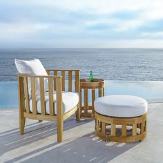 two wooden chairs sitting next to each other on top of a cement floor near the ocean