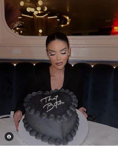 a woman sitting at a table with a cake in front of her