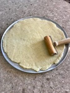 an uncooked pizza dough on a pan with a rolling pin resting on it