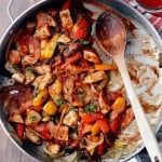 a pan filled with chicken and vegetables on top of a table