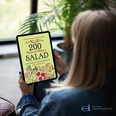 a woman holding up a book about how to make a salad