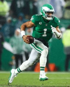 a football player running with the ball in his hand and wearing a green uniform on