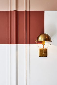 a wall light mounted on the side of a white and red wall next to a door