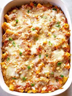 a casserole dish filled with pasta and meat covered in sauce, cheese and green onions