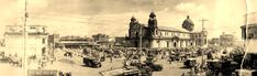 an old black and white photo of people on the street with buildings in the background