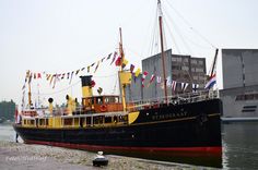 a large black and yellow boat sitting in the water next to a dock with flags on it