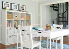 a white table and chairs in front of a bookshelf with pictures on it