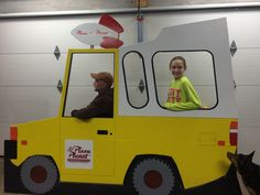 two children are sitting in the back of a yellow truck that is made to look like a pizza hut