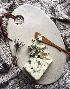 cheese and herbs on a cutting board with a wooden spoon