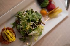 a white plate topped with a salad next to other food on top of a table