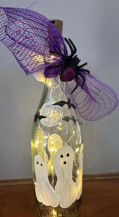 a bottle with some lights in it and two ghostes on the inside, sitting on a table