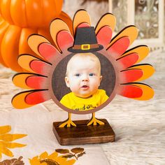 a baby wearing a thanksgiving turkey hat is shown in front of a table with pumpkins