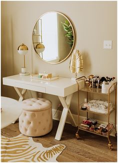 a white desk with a mirror, stool and gold accessories on it in a room