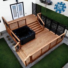 a hot tub sitting on top of a wooden deck next to a white building with black doors