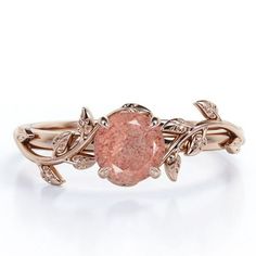 a pink diamond ring with leaves on the band and an oval stone in the center