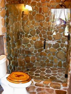 a bathroom with stone walls and a toilet in the shower stall is seen here,