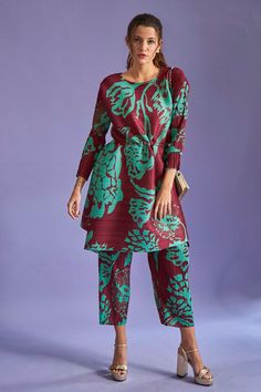 Maroon pleated tunic with green floral printed motifs and drawstring at the waist. Comes with co-ordinating wide leg pants.
Component: 2
Pattern: Print
Type Of Work: Floral Print
Neckline: Round
Sleeve Type: Full
Fabric: Pleated Fabric
Color: Maroon
Other Details: 
Asymmetrical hem
Tie up at the back
Note: Sling bag carried by the model is not for sale
Occasion: Resort - Aza Fashions Floral Print Tunic, Pleated Fabric, Fabric Print, Print Tunic, Pant Set, Asymmetrical Hem, Set For Women, Festival Wear, Floral Printed