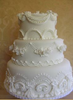 a three tiered wedding cake with white frosting