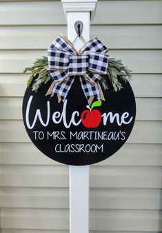 a welcome sign hanging from the side of a building with an apple on it's front door