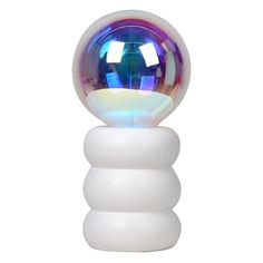 a glass ball sitting on top of a white stand with a rainbow light in it