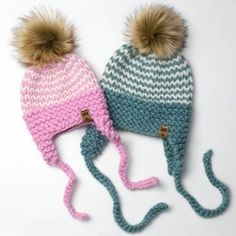 two knitted hats with pom - poms on them