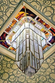 the stained glass window in the ceiling is very intricately designed and looks like an art deco