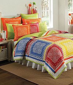 a bed room with a neatly made bed and colorful comforter sets on the floor