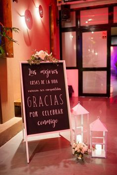 a sign that is sitting on the ground in front of a building with flowers and candles