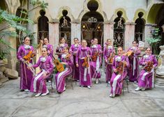 a group of women in purple outfits are posing for a photo with guitars and violines