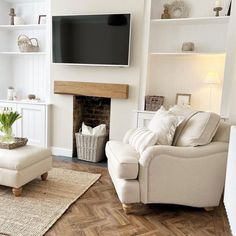 a living room with white furniture and a large flat screen tv mounted above the fireplace